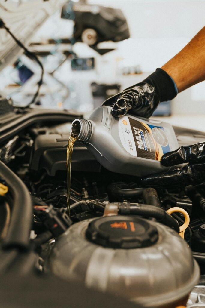 pexels-photo-13065694-13065694 A close-up of a mechanic in gloves pouring engine oil into a car engine, showcasing automotive maintenance.