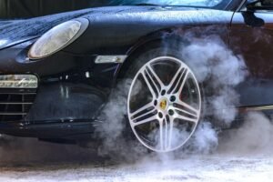 Close-up of a luxury car wheel with steam and water droplets, showcasing power and style.